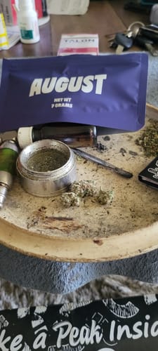 Reviewer's Granddaddy Purp buds on a tray with a grinder and the purple product packaging in the background.