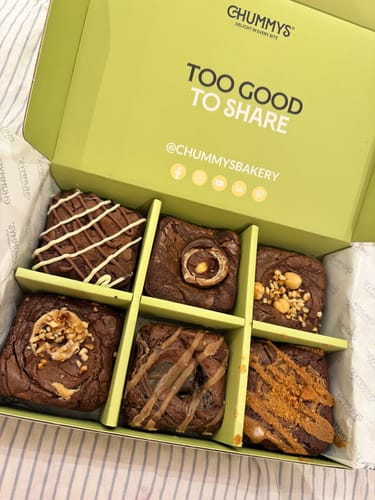 Customer's open Postal Brownie Box showing six rich, assorted brownies neatly arranged in dividers.