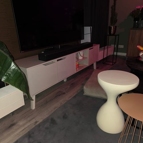 Recensent toont het greige by fonQ Nordo tv-meubel in een sfeervol verlichte woonkamer, met een tv en soundbar erop.