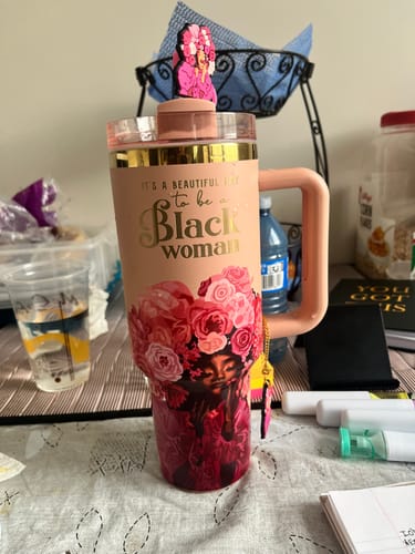 Customer's Rose Pink tumbler with its handle, straw topper, and detailed floral illustration of a Black woman.
