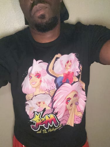 Customer wearing the black Singer Collage Jem And The Holograms T-Shirt with its colorful graphic.