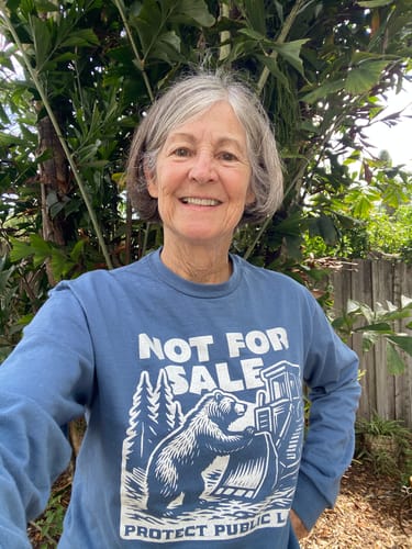 Reviewer smiling outdoors in the blue Not For Sale Public Lands Bulldozer Long Sleeve Tee.