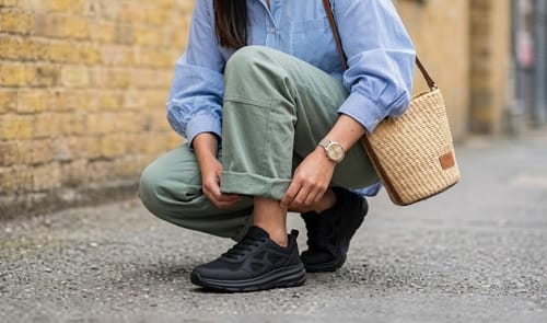 Reviewer crouching outdoors in black Motion X shoes with cuffed green pants.