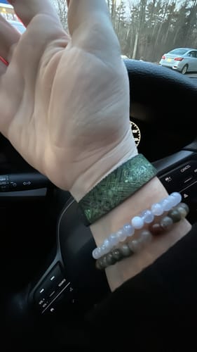 Close-up on a reviewer's wrist wearing the green patterned 'May The Road Rise To Meet You' bracelet.