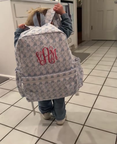 Reviewer's toddler from behind, wearing the large patterned Backpack which appears oversized on the child.