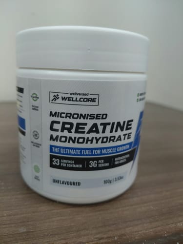Customer's white tub of Wellcore Micronised Creatine Monohydrate shown on a wooden surface.