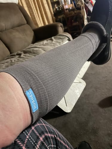 Close-up of a reviewer's leg wearing the grey Performance Eucalyptus Compression Socks indoors.