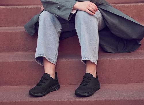 Reviewer sitting on stairs wearing the black Balance Pro shoes with light-wash jeans.