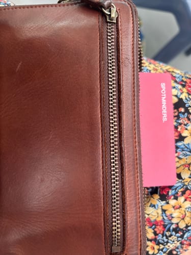 Close-up of the reviewer's brown leather Trackable Passport Cover, used as a wallet.