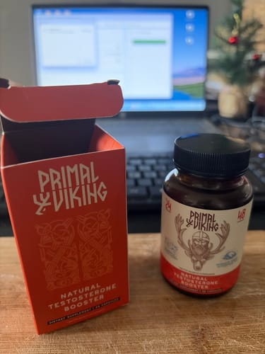 Reviewer's bottle and red box for Primal Viking testosterone support on a wooden desk.