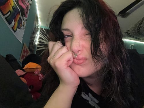 Close-up of a reviewer winking while wearing the Spiked Heart Septum.