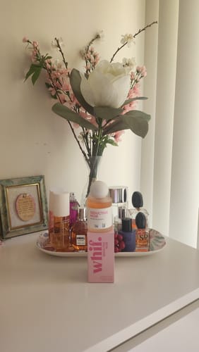 Customer's Seductive Noir perfume bottle and pink box displayed on a white vanity among other fragrances.