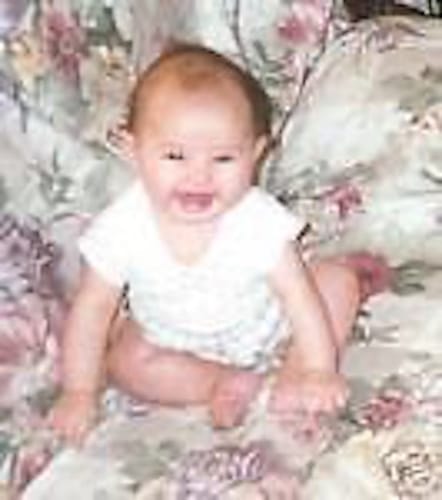 A customer's submitted photo of a smiling baby on a floral surface.