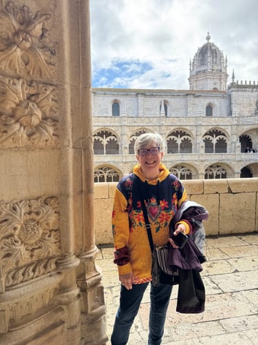 Reviewer wearing the colorful Virgen Las Flores hoodie at the Jerónimos Monastery in Lisbon.