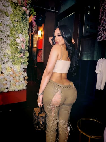 Reviewer showing the back of the tan Vice Pant with lace-up details at a restaurant.