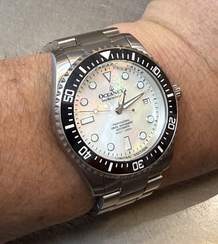 Customer wearing the Oceaneva Deep Marine Explorer II watch, showing its white mother-of-pearl dial and titanium band.