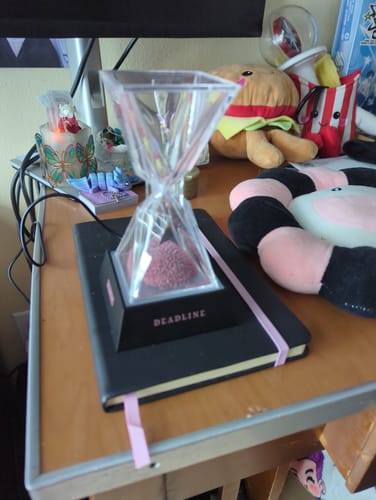 Customer's BLACKPINK DEADLINE Moodlight, an hourglass on a black base, sitting on a notebook on a desk.
