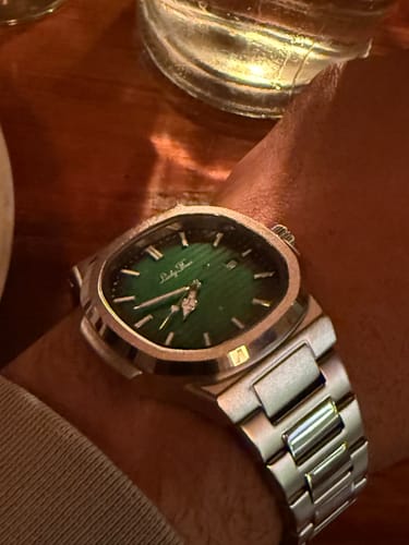 Close-up of a reviewer's Lucky Fours Caspian watch, showing the green dial and silver band on their wrist.