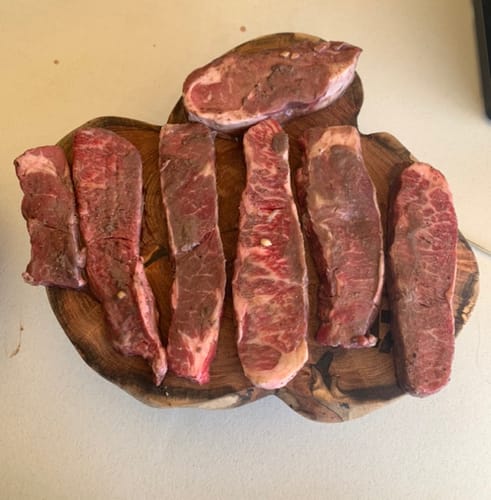 Reseña de un cliente que muestra Tablitas de Lomo crudas y sazonadas en una tabla de cortar de madera.