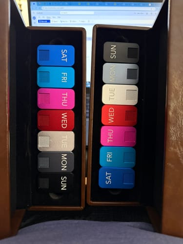 Reviewer's two sets of colorful MagNano Case pill organizers for each day of the week in their boxes.