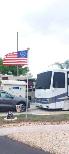 Customer's Betsy Ross flag flying on a flagpole in front of a large RV at a campsite.