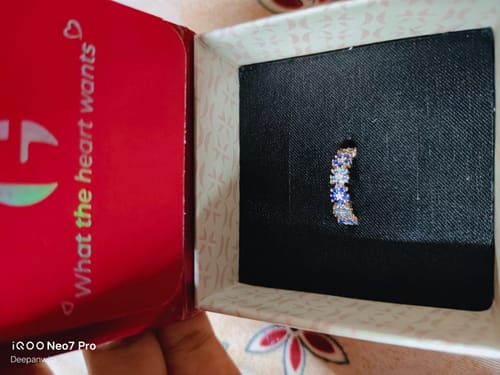 Customer showing a ring with blue and clear stones sitting inside its red presentation box.