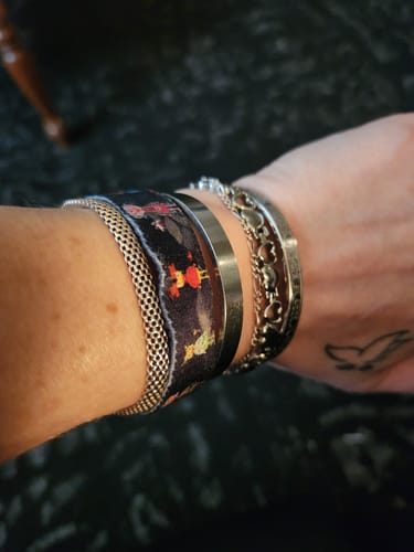 Close-up of a customer's wrist showing the patterned Choose Today Bracelet worn stacked with other bracelets.