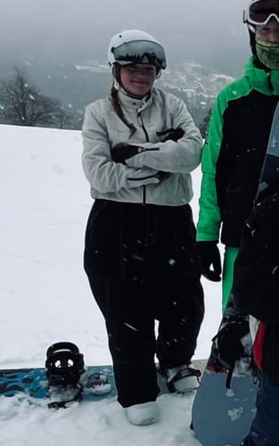 Reviewer standing in the snow, wearing the black baggy Oxford workwear snow pants with a light-colored jacket.