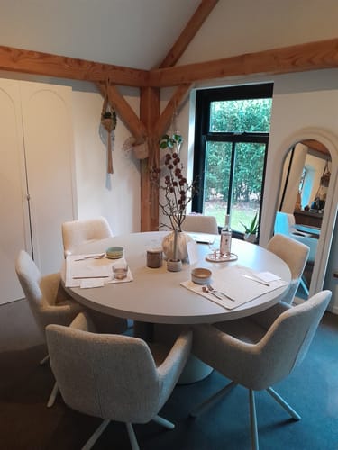 Klant toont de ronde Kave Home Nealy eettafel in een sfeervolle eetkamer, gedekt voor zes personen.