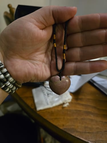 Customer holding a heart-shaped stone pendant necklace from their AuraBloom Subscription Box.