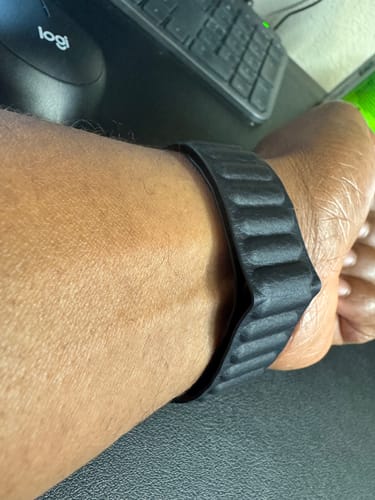 Close-up of a customer wearing the black Leather Link Magnetic Strap on their wrist at a desk.