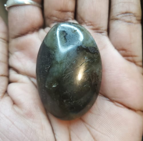 Customer holding a smooth, dark Labradorite Moonstone crystal in their hand.