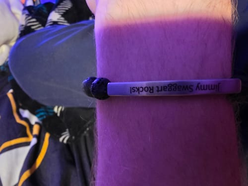 Close-up of a customer wearing a purple Lava Custom Bracelet on their wrist, engraved with 'Jimmy Swaggart Rocks!'.