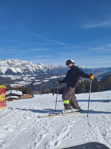 Customer on a ski slope wearing the baggy, coffee-colored waterproof snow pants.
