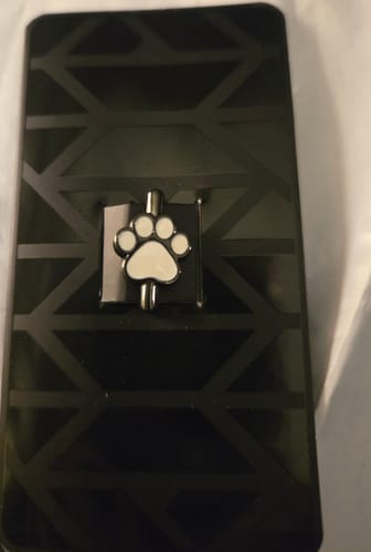 Customer's Cat Paw Charm on its original packaging, placed on a black patterned surface.