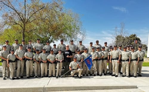 Reviewer wearing the black Keep Moving Forward t-shirt while posing with a large group of academy cadets outdoors.
