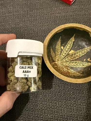 Customer holding a full jar of CALI MIX AAA+ premium flower next to a decorative bowl.