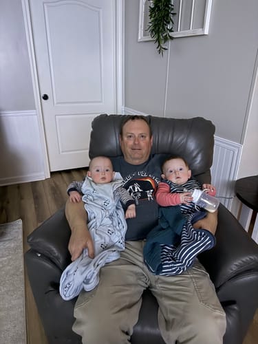 Reviewer holding two babies, one wearing the panda print 4 Season® Ultimate Baby Sleep Bag.