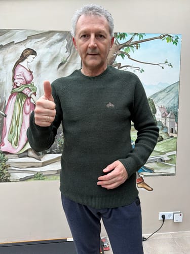Kunde trägt den dunkelgrünen Strickpullover "Lodge" und macht eine Daumen-hoch-Geste.