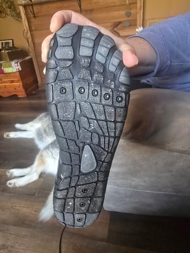 Customer holding up a Lorax Pro barefoot shoe to show the textured, non-slip sole.