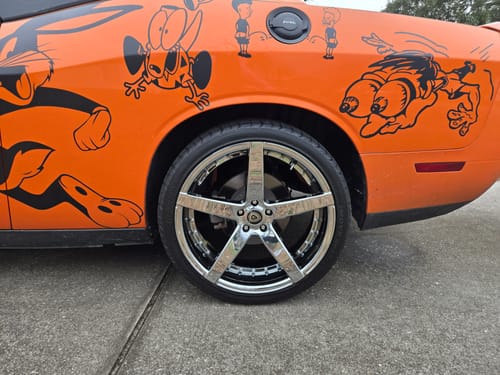 Customer's orange car covered in custom black vinyl decals of cartoon characters.