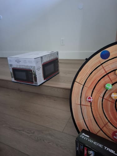 Customer's image showing a microwave box and a dart game on a wooden floor, unrelated to the cookie product.