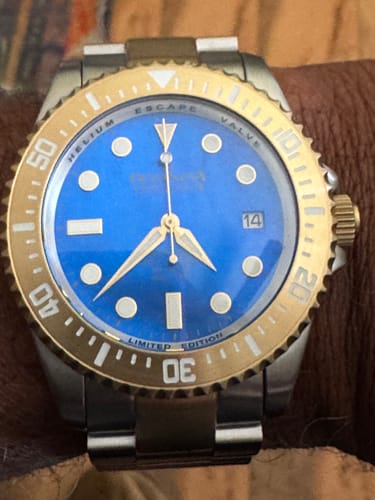 Close-up of the customer's Oceaneva Pro Diver watch, showing the vibrant blue dial and yellow gold bezel.