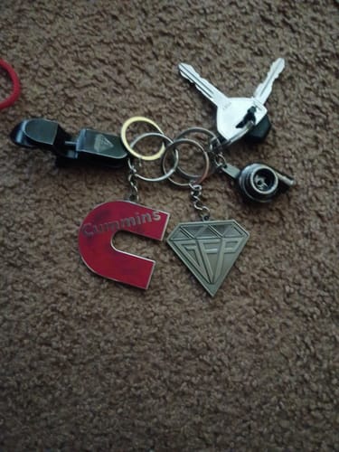 Customer's red Cummins keychain on a key ring with other charms and keys, placed on a brown carpet.