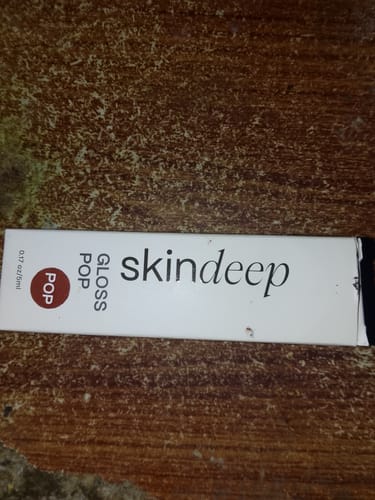 Box containing a customer's skindeep Gloss POP High-Shine Lip Gloss on a wooden surface.