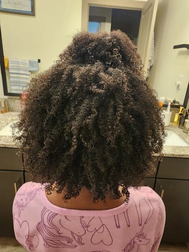 Customer shows the back of a child's head with defined, coily hair after using the Tropical Oasis Hair Gel.