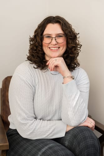 Reviewer smiling while wearing the delicate Nara Necklace with a light-colored sweater.