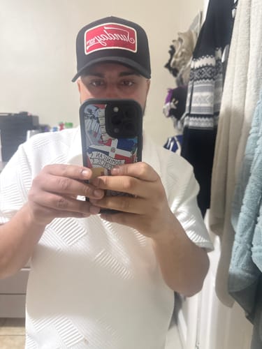 Reviewer taking a mirror selfie while wearing the black VINTAGE SNAPBACK hat with a red and white logo.