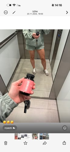 לקוחה מחזיקה בקבוק Tumm it בידה מול מראה במעלית.