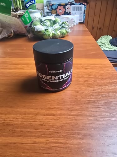 Customer's black tub of Essentials Multivitamin sitting on a wooden table.